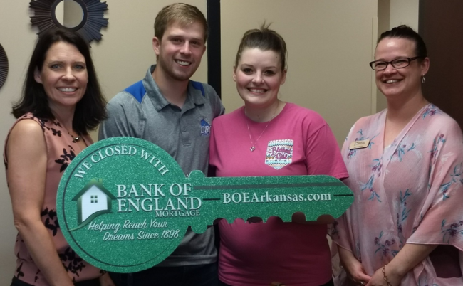 Group of four people holding oversized Bank of England Arkansas key